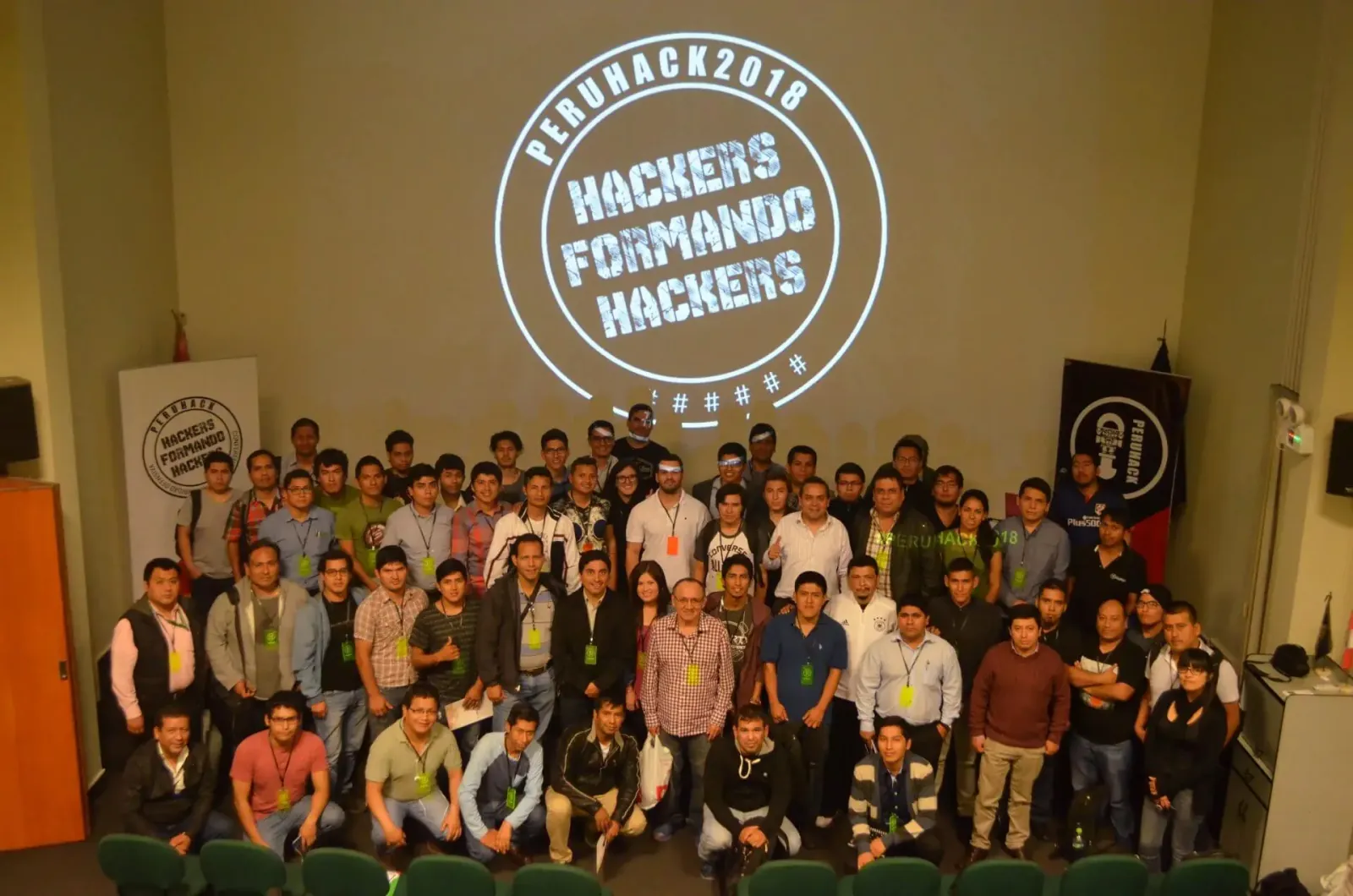 Foto grupal de PERÚHACK 2018 bajo el lema Hackers formando hackers proyectado en la pantalla
